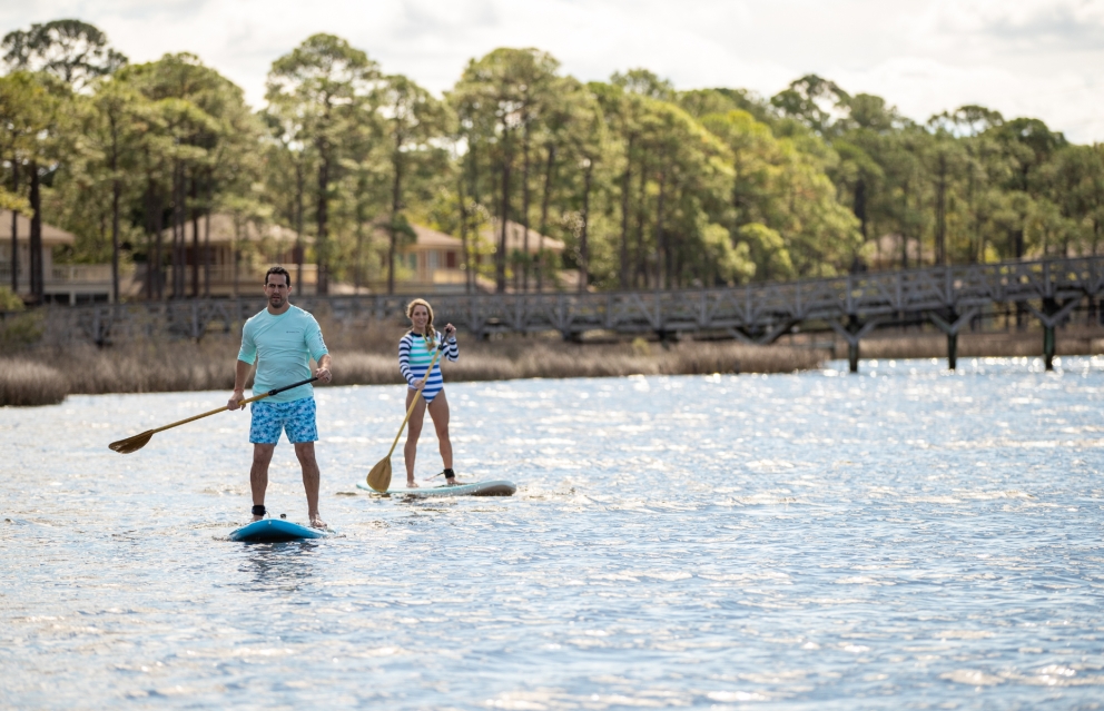 A couple stand-up paddle-boarding.