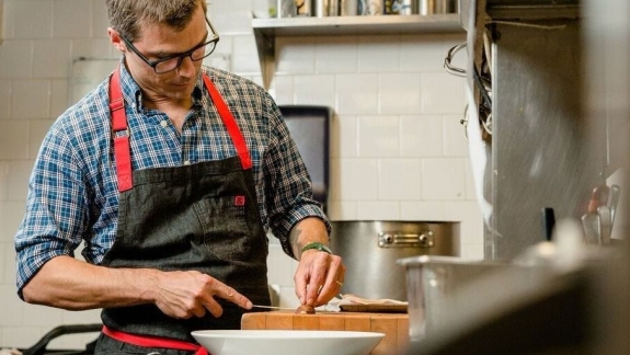 Chef Hugh Acheson in kitchen preparing a meal.