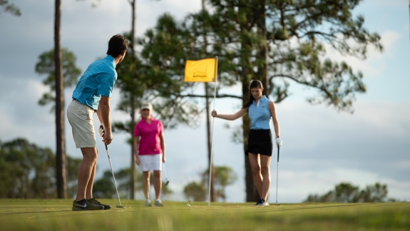 A man makes a putt on a golf green.