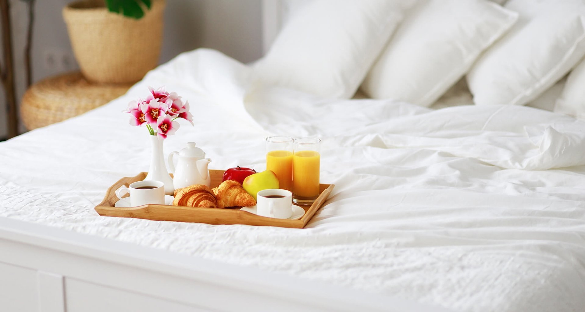 A fresh breakfast on a tray on a bed with white linens.