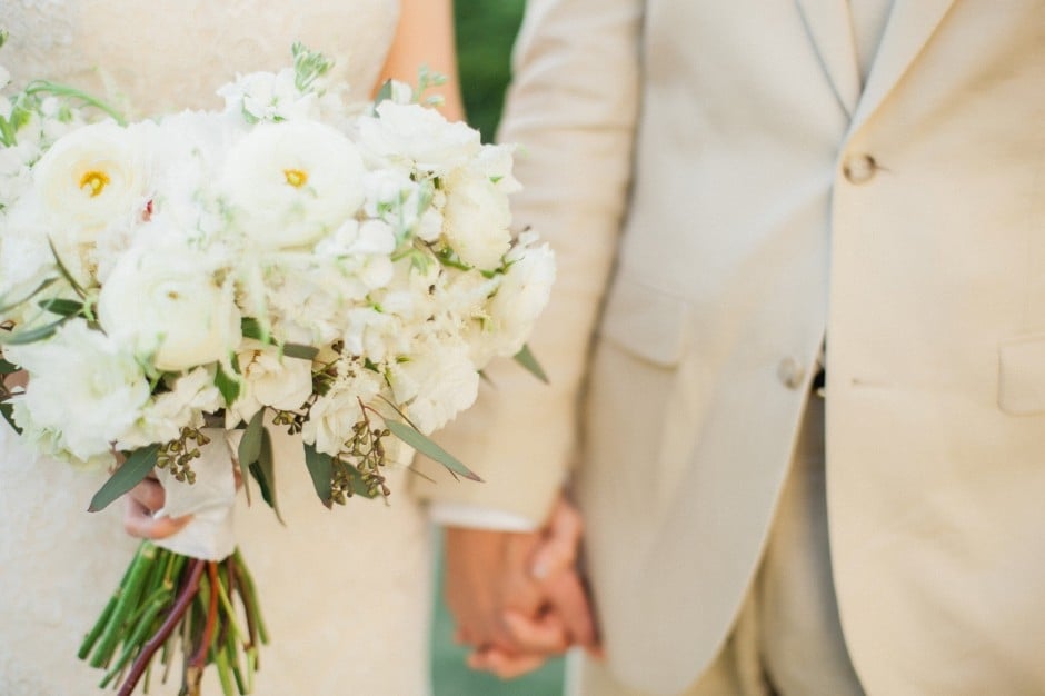 Close up of a bride and groom holding hands