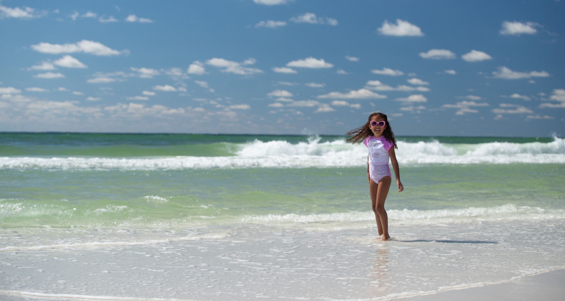 A young girl walks on a white sand beach at Hotel Effie