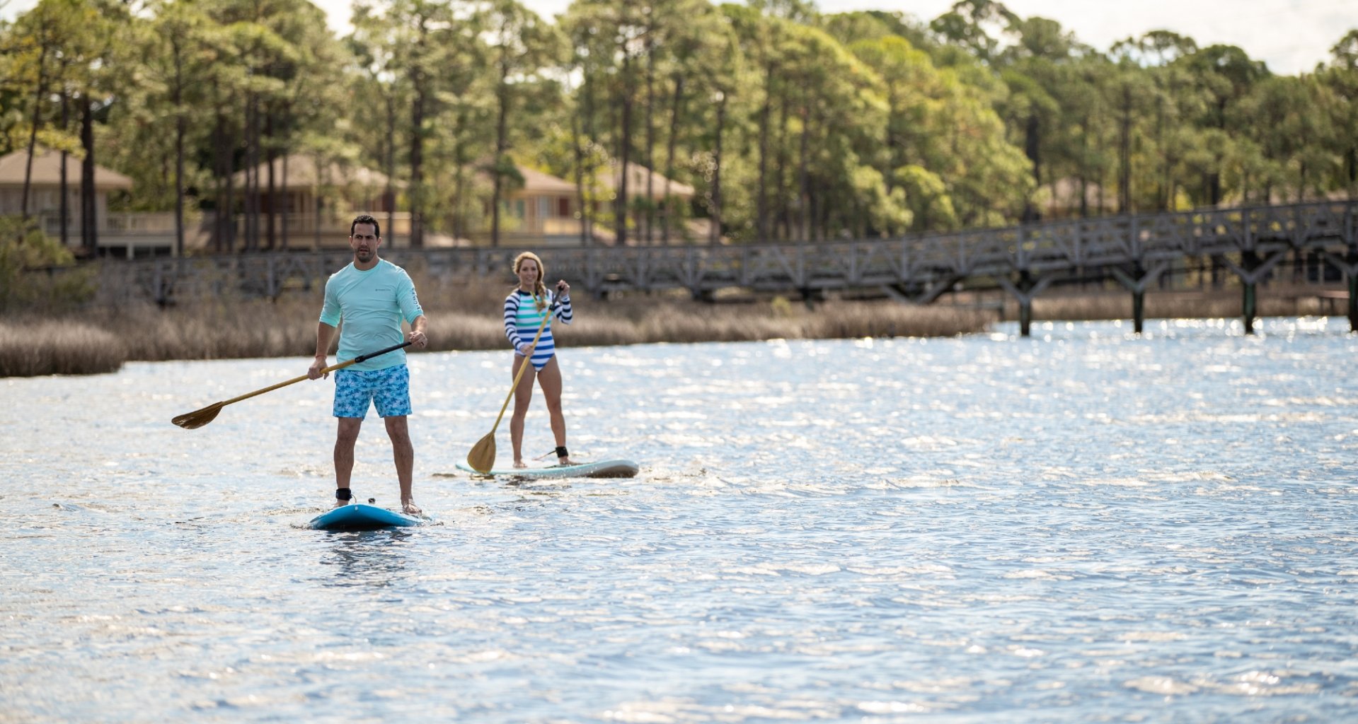 A couple stand-up paddle-boarding.