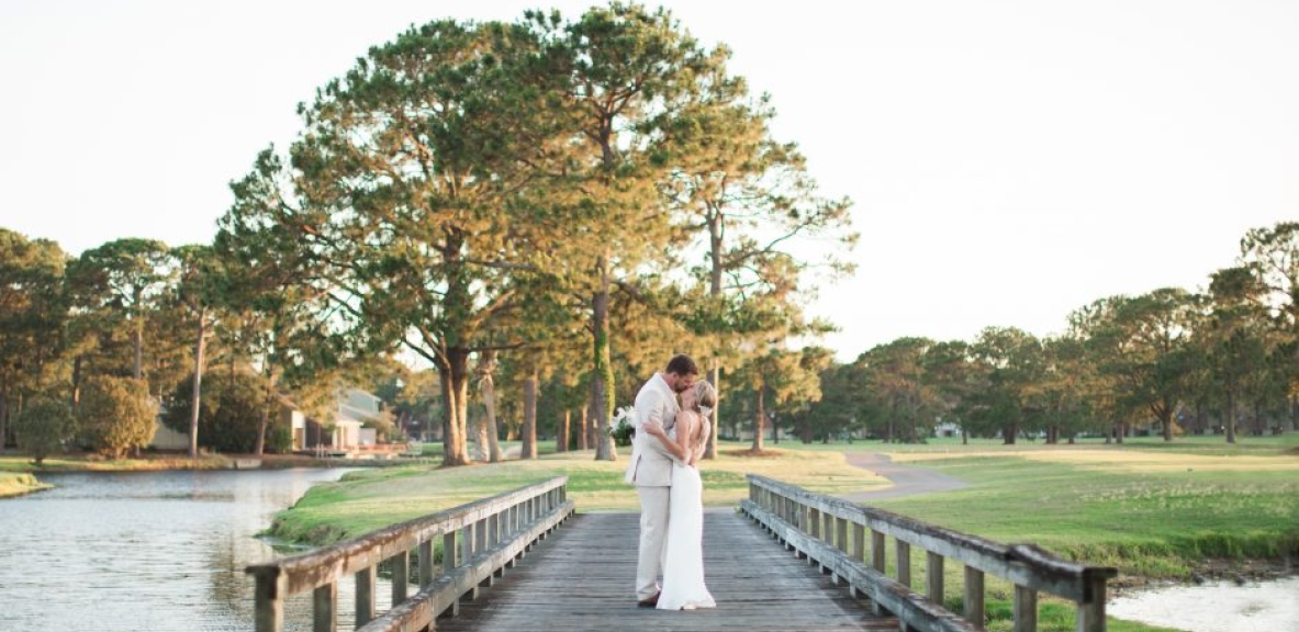 Bride and groom kissing on a bridge during their Destin, Florida wedding.