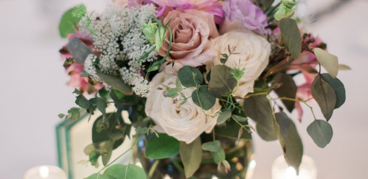 Close up on a centerpiece of flowers and candles.