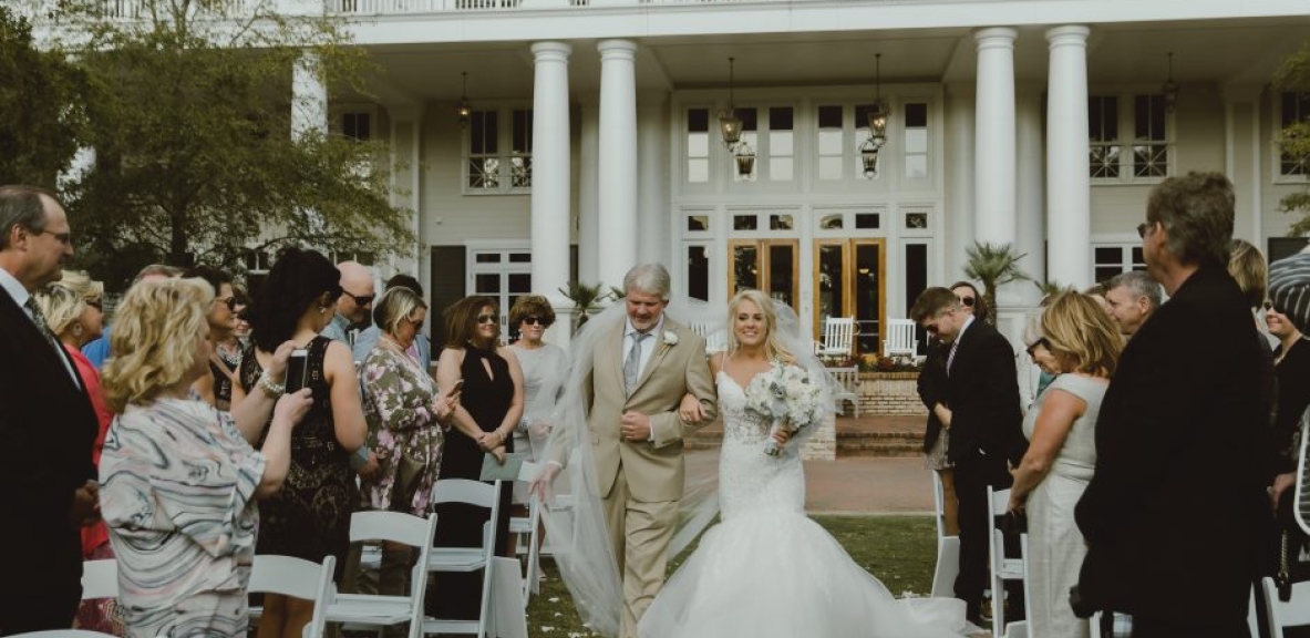 Caryn being walked down the aisle at her outdoor Destin, Florida wedding.