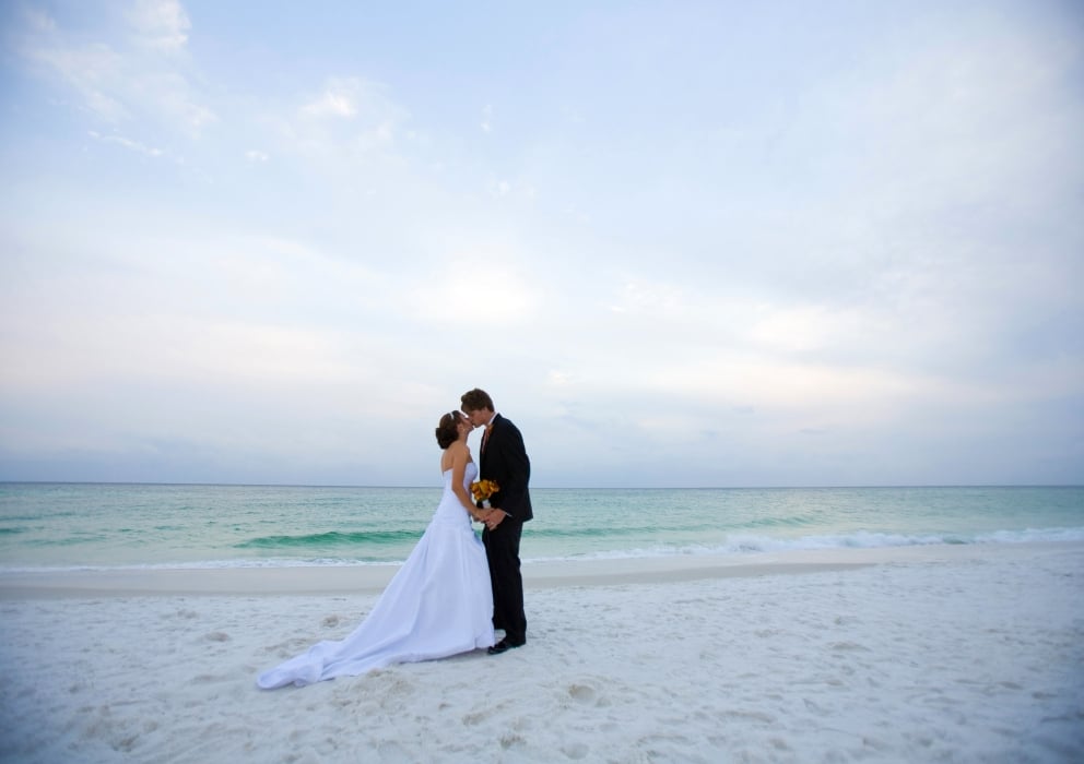 A bride and groom kissing on the beach