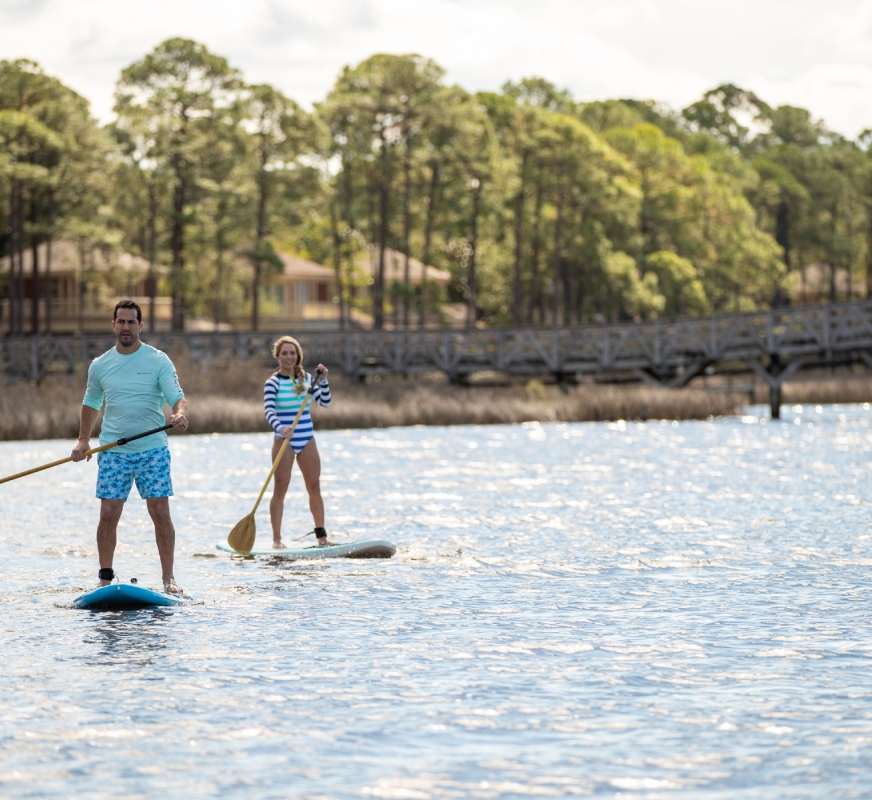 A couple stand-up paddle-boarding.