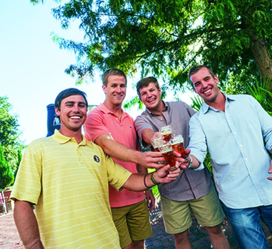 A group of guys smiling and holding their drinks